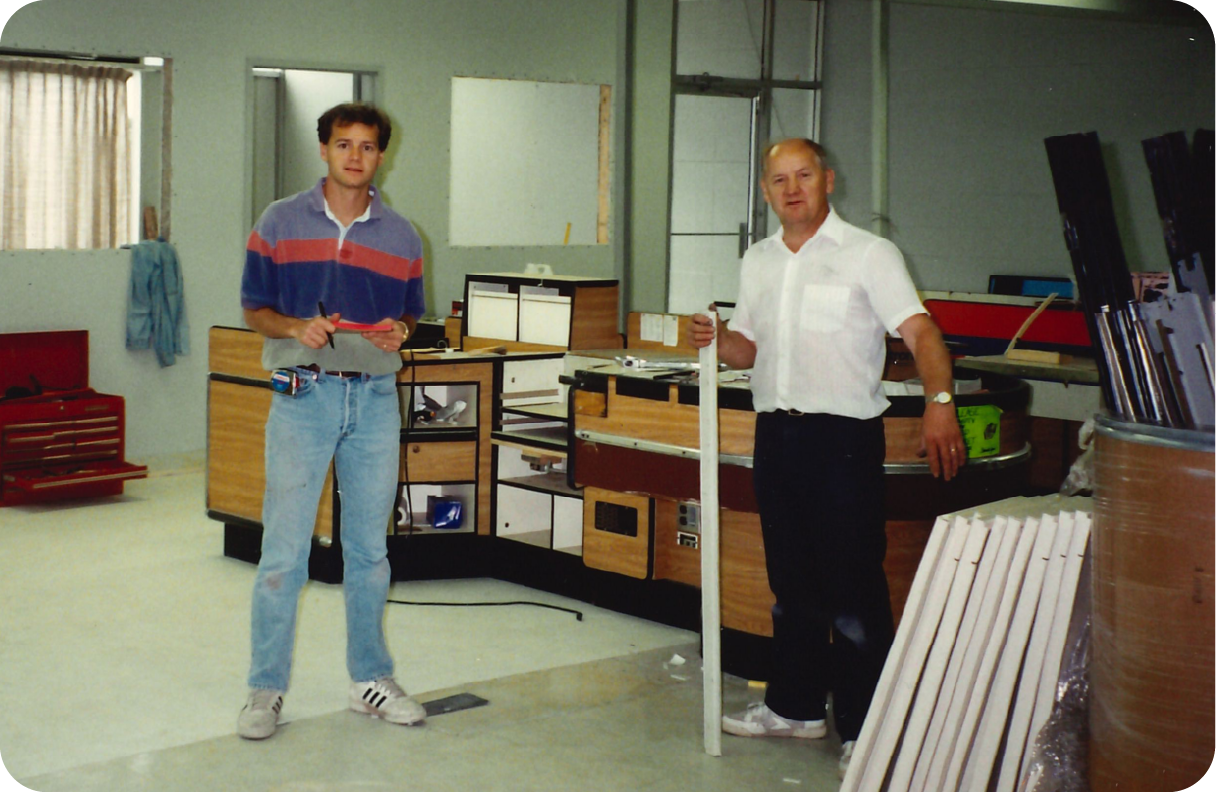 The two founders standing inside an MTF store in 1985